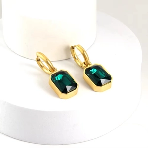 Dettaglio macro di orecchini d'oro con pietre di zircone rettangolari verde smeraldo