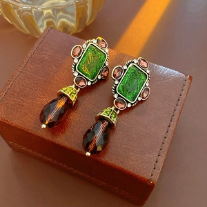 Detail of vintage gold earrings with green rectangle stone and red teardrop pendant