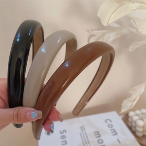 Close-up of three retro wide leather-style headbands in black, beige, and brown colors