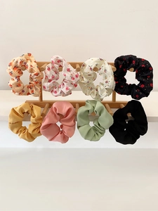 Set of 8 chiffon bow hair scrunchies in floral and pastel colors on a wooden display