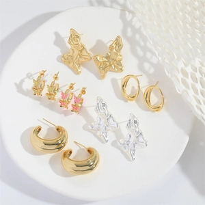 Minimalist gold and silver butterfly earring set with hoops and textured studs on a white tray