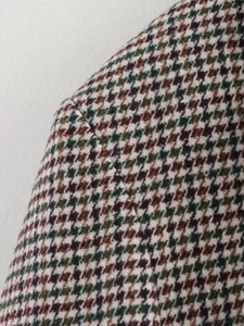 Detailed macro shot of houndstooth wool fabric in brown, green and beige tones