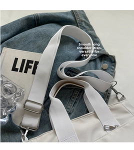 Détail de la bandoulière réglable avec boucle en métal argenté sur un sac fourre-tout blanc