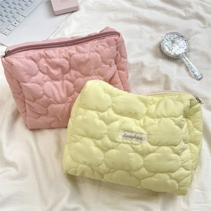 Nahaufnahme der rosa und gelben Stepp-Kosmetiktaschen mit Herz- und Wolken-Stickmustern