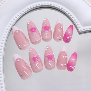 Faux ongles amande avec perles 3D, motifs floraux et strass sur un miroir élégant