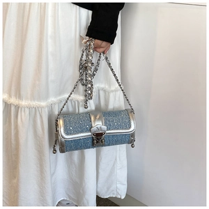 Detail of blue denim cylinder bag with silver leather trim and metal chain strap