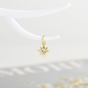 Macro view of gold North Star pendant with white zircon on a white branch stand