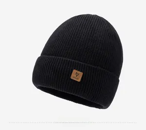 Detail of black ribbed knit beanie featuring a brown faux leather logo patch on the cuff