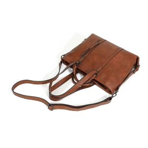 Detail of caramel brown faux leather tote bag with dual handles and removable strap