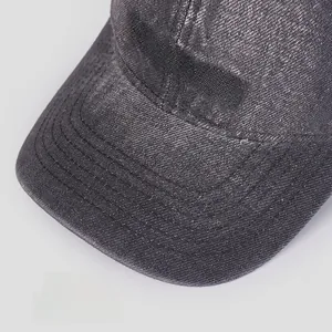 Detailed view of red CONQUER embroidery on washed grey denim baseball cap brim