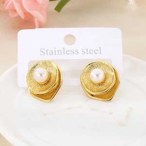 Detail of gold titanium steel earrings with white pearls on white ceramic tray
