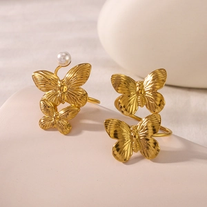 Elegant 18k gold butterfly earrings with white pearls on a minimalist display