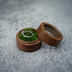 Detail of round walnut wood ring box with green moss lining and clear window