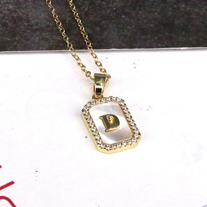 Detailed macro view of 18K gold letter D rectangular pendant with shell and cubic zirconia