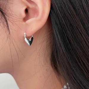 Minimalist 925 sterling silver heart-shaped stud earrings worn by a model