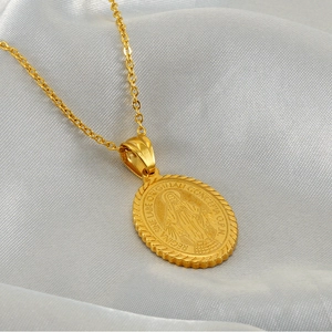 Golden religious necklace featuring an oval Virgin Mary relief pendant on white silk fabric