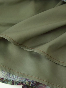 Macro detail of military green chiffon fabric with fine stitching and golden thread print
