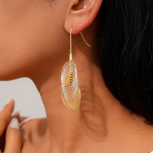 Detail of mixed-metal multi-layer geometric hoop earrings on a fashion model