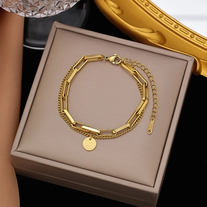 Detail view of double-layered gold stainless steel bracelet with a round pendant in a box