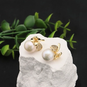 Elegant gold flower pearl earrings with zircon inlay on a textured white stone base