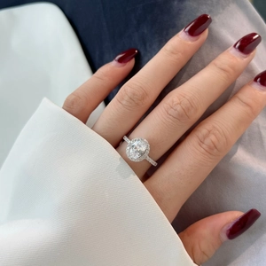 Detailed view of an oval halo S925 silver ring with pavé setting on a model's hand