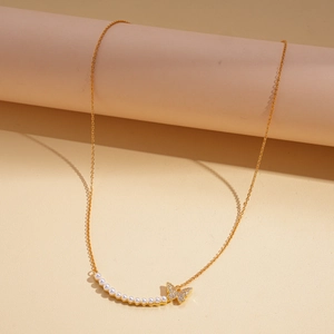 Macro detail of 18k gold plated butterfly pendant necklace with pearls and rhinestones