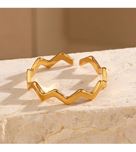Detail view of wavy 18K gold-plated open ring on natural stone texture