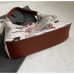 Détail du sac hobo blanc avec imprimés graffiti colorés et bandoulière en cuir marron