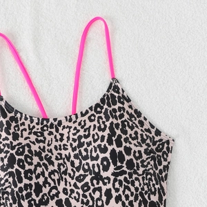Details von Badeanzug mit Leopardenmuster und neonpinken Trägern auf weißem Grund