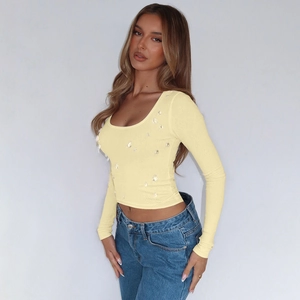 Dettaglio di un crop top a coste giallo pallido a maniche lunghe con scollo a U