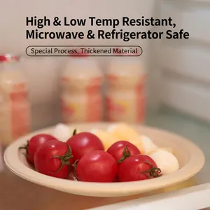 Biodegradable sugarcane pulp round plate holding fresh cherry tomatoes and white snacks
