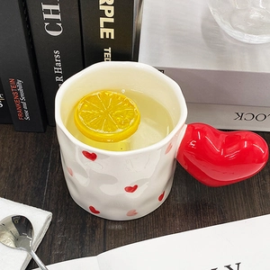 Detail of white ceramic mug with red heart-shaped handle and lemon slice in water
