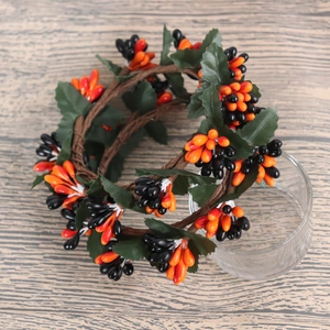 Macro detail of Halloween candle ring with orange black berries and foliage on wood background