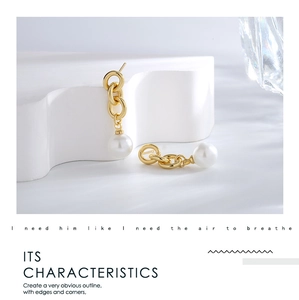 Detail of gold-plated multi-link earrings featuring a round pearl on a white pedestal