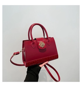 Détail d'un sac à main en cuir rouge foncé avec motif crocodile et boucle dorée