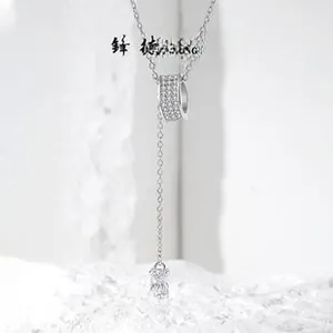 Macro detail of S925 sterling silver Y-necklace with paved cylinder and tassel zircon