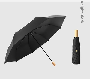 Detail of Knight Black folding umbrella featuring premium wood handle and gold button