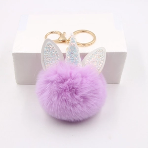 Detailed view of a purple plush unicorn keychain with gold clasp and glitter horn detail