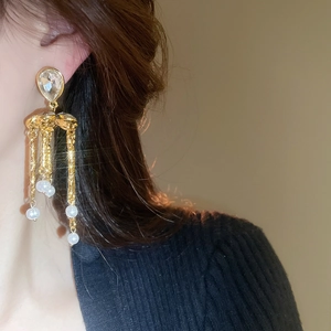 Gros plan de boucles d'oreilles dorées à pampilles avec cristaux et perles sur modèle