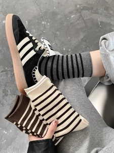 Detail of striped knitted cotton crew socks in dark brown, black, and beige colors