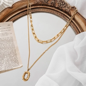 Gold double-layered necklace featuring paperclip chain and irregular oval pendant