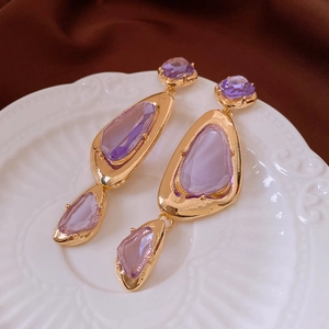 Detailed macro view of vintage gold drop earrings with purple faceted crystals