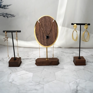 Three walnut wood and gold metal jewelry stands for necklaces and earrings on marble
