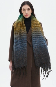 Detail view of a multicolored gradient winter scarf with decorative fringe on a model