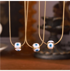 Detailansicht der goldenen Schlangenkette mit weißen Evil Eye Tropföl Anhängern in Würfelform