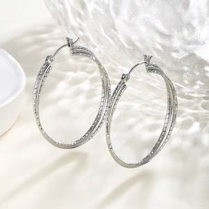 Detailed close-up of silver double-hoop earrings featuring a unique hammered texture finish