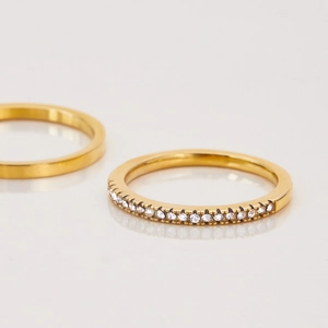Vue macro de deux bagues en titane doré avec pavé de zircons et finition lisse