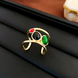 Detailed macro view of an adjustable gold-plated ring with red, black and green oval zircons