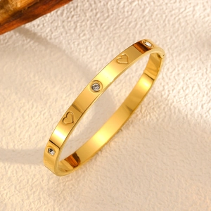 Détail du bracelet doré ondulé avec gravures de cœur et incrustations de cristaux