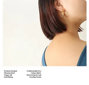 Gros plan de boucles d'oreilles en titane plaqué or 18k avec perles portées par un mannequin